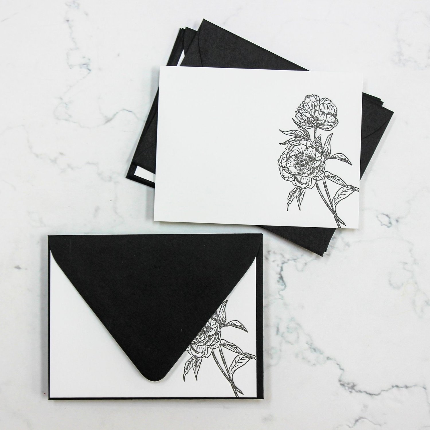 Letterpress correspondence cards with black envelopes on a marble surface